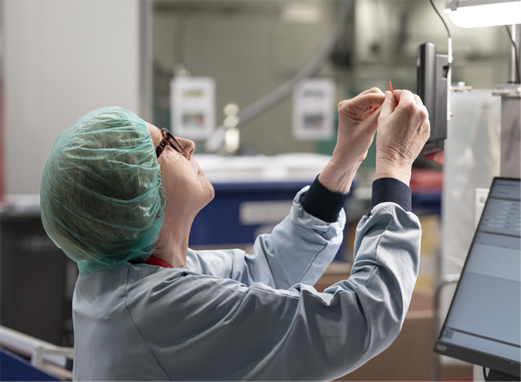 Een kwaliteitsmedewerker controleert een kunststofproduct in de productieafdeling van HDB.